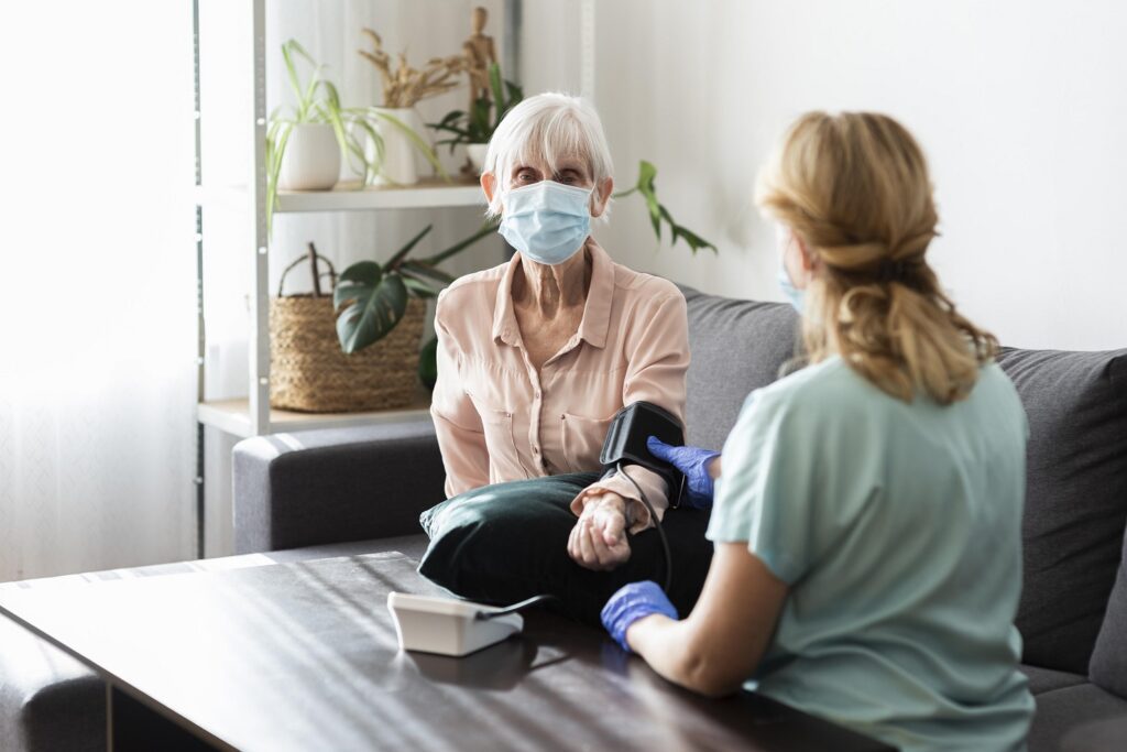 elder-woman-with-medical-mask-having-her-blood-pressure-checked-nursing-home - Copy